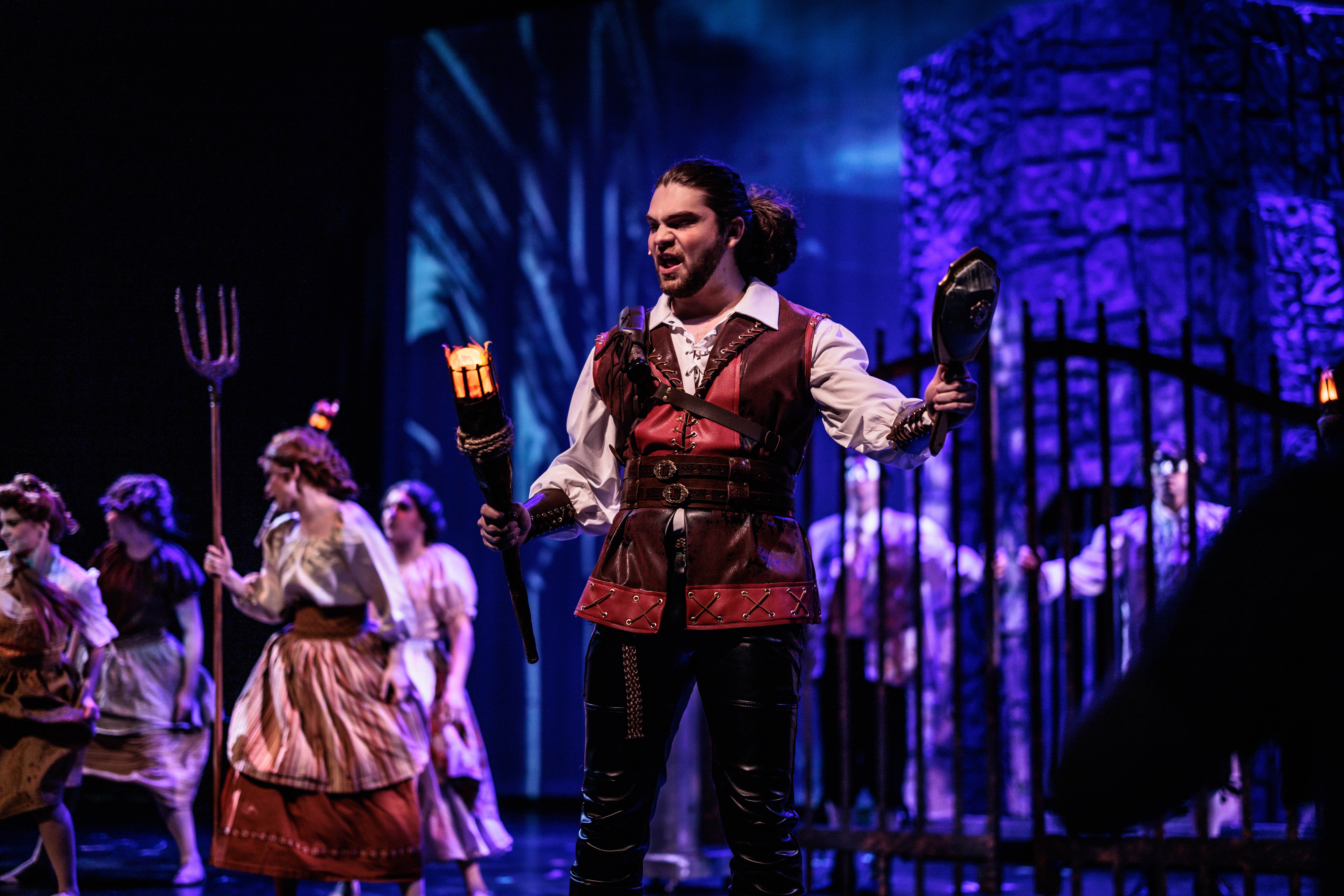 Holding a torch and mirror on stage